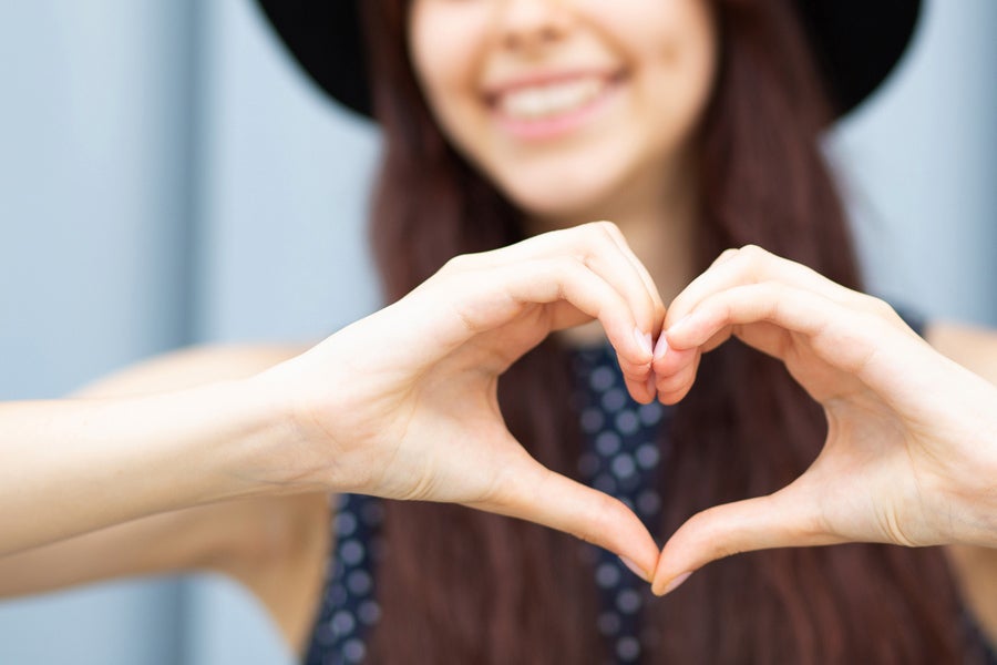 Woman smiling and holding a heart with her hands